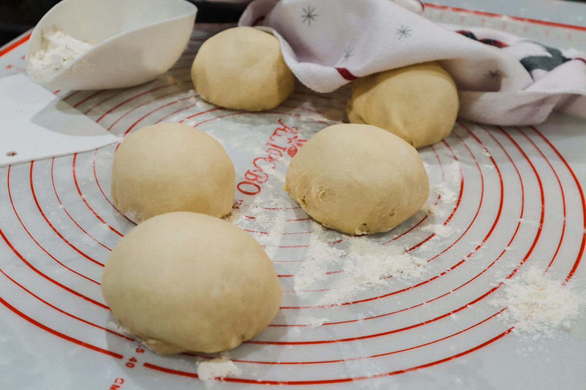 Panetti di pasta brioche, stesi su tappeto di silicone, pronti per seconda lievitazione.