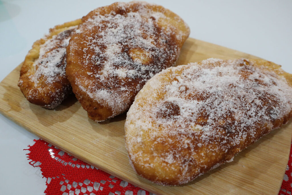 Raviole di ricotta intere, spolverate di zucchero semolato.