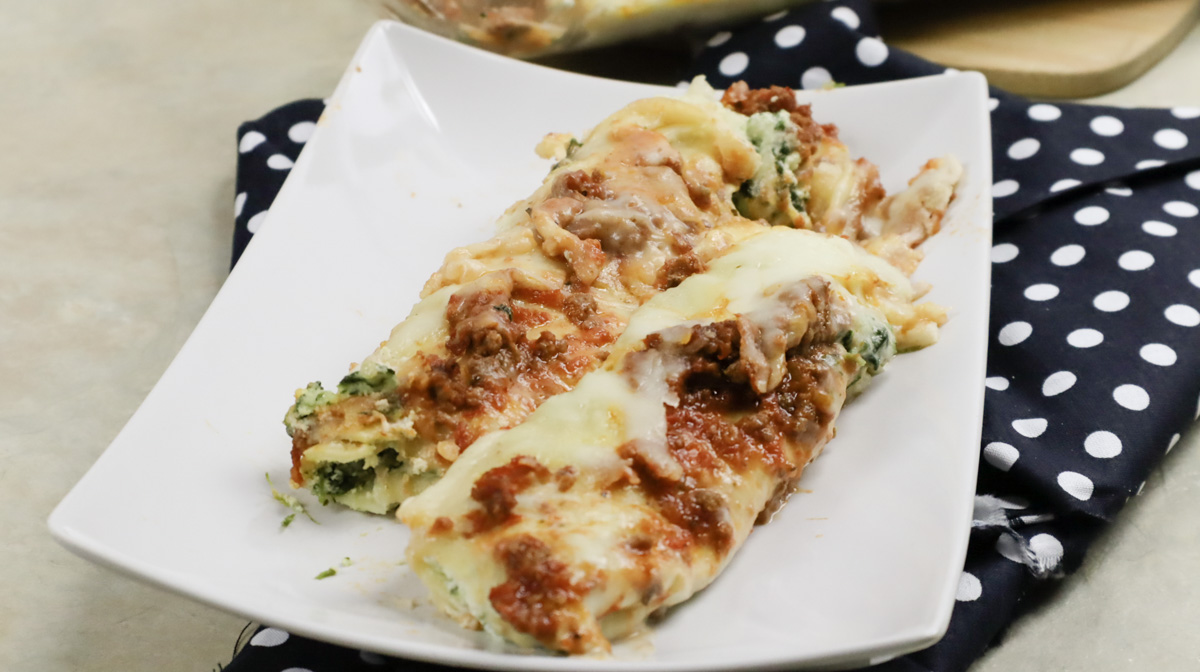 Cannelloni con ricotta e spinaci presentato su piatto di ceramica.