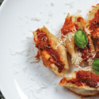 Conchiglioni ripieni al forno con ricotta su piatto bianco.