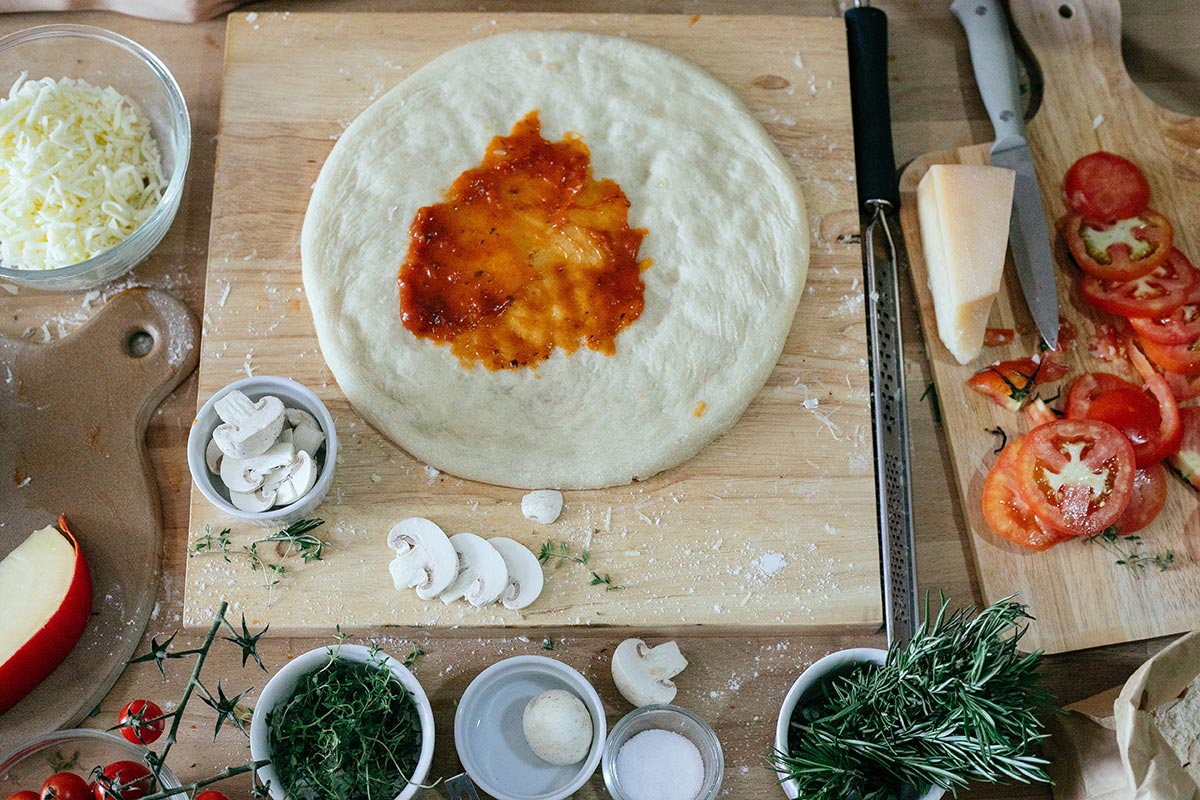 Impasto steso pronto per essere condito e messo in forno.