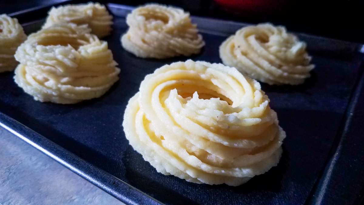 Purè di patate, a forma di nido, su una teglia da forno. Pronti a infornare.