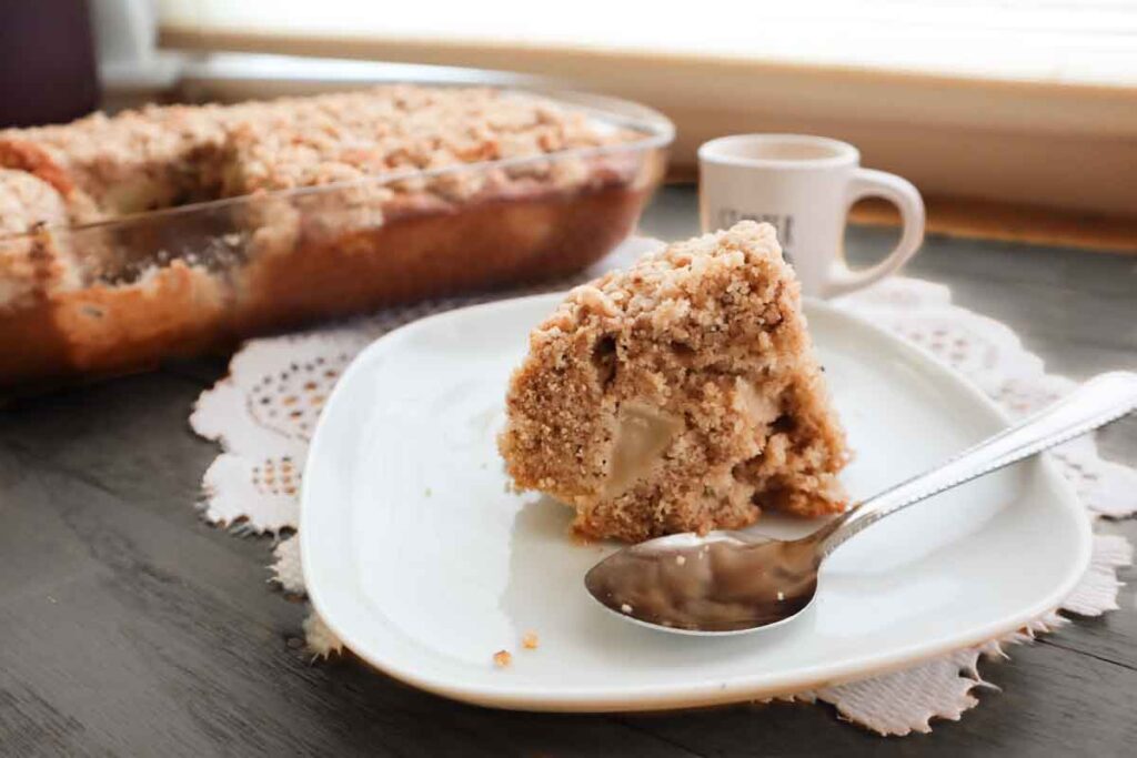 Una fettina in primo piano su piatto di ceramica, con un cucchiaio al fianco e una tazzina di caffè espresso alle spalle.