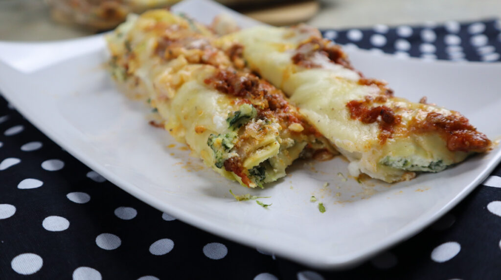 Cannelloni ricotta e spinaci pronti per essere gustati su piatto di ceramica.